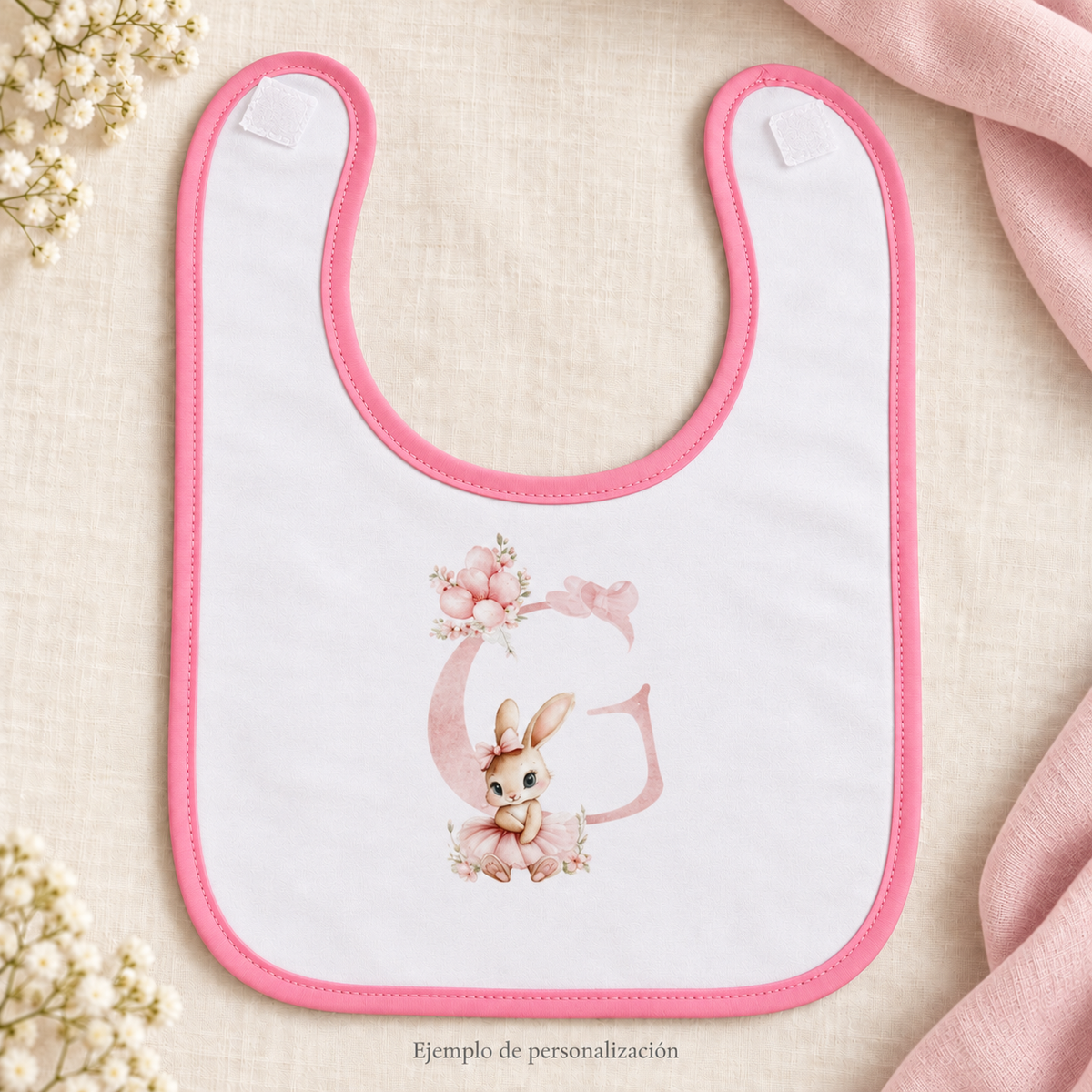 Ejemplo de personalización: babero blanco con ribete rosa, inicial G con flores y conejita.